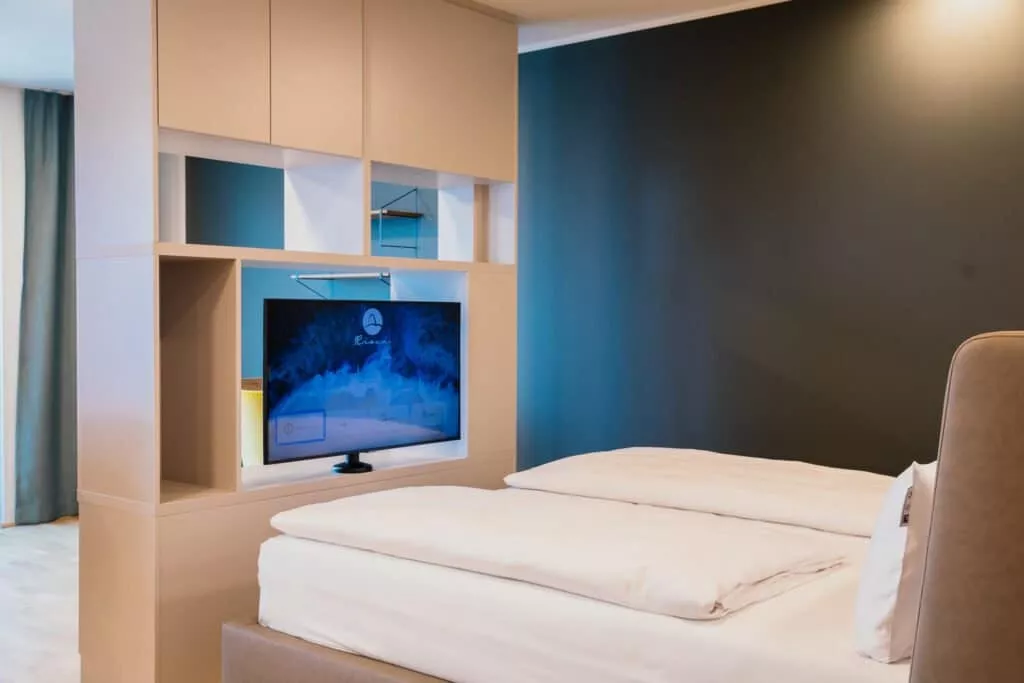 Großes Bett mit weißem Laken und TV