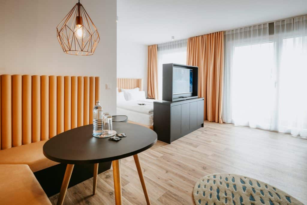 schwarzer Esstisch vor Doppelbett und TV