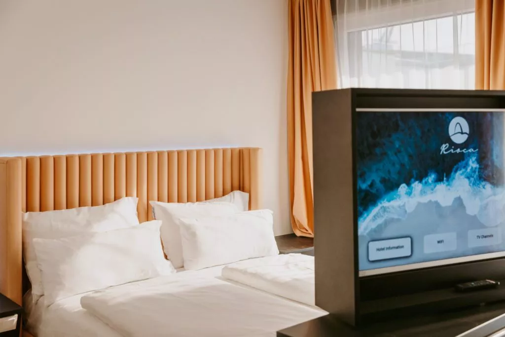 Doppelbett mit weißem Laken vor TV