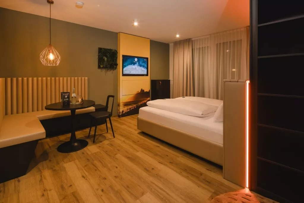 Hotelzimmer mit Bett, Sitzecke und TV bei Nacht