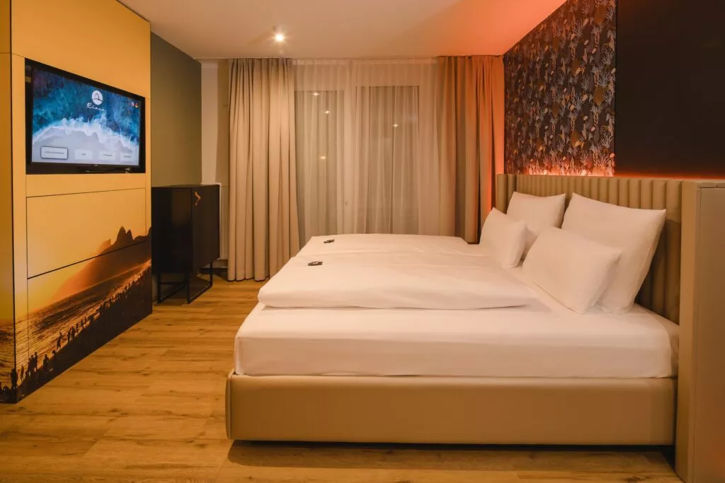 Großes Doppelbett und TV vor großem Fenster in Hotelzimmer