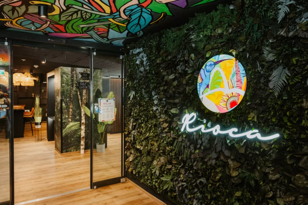 Wand mit grünen Pflanzen und buntem Logo darauf