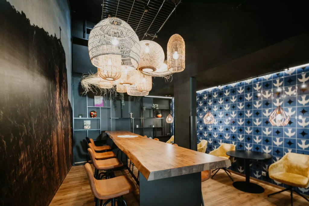 Großer Holztisch mit Deckenleuchten vor blauer Fließenwand