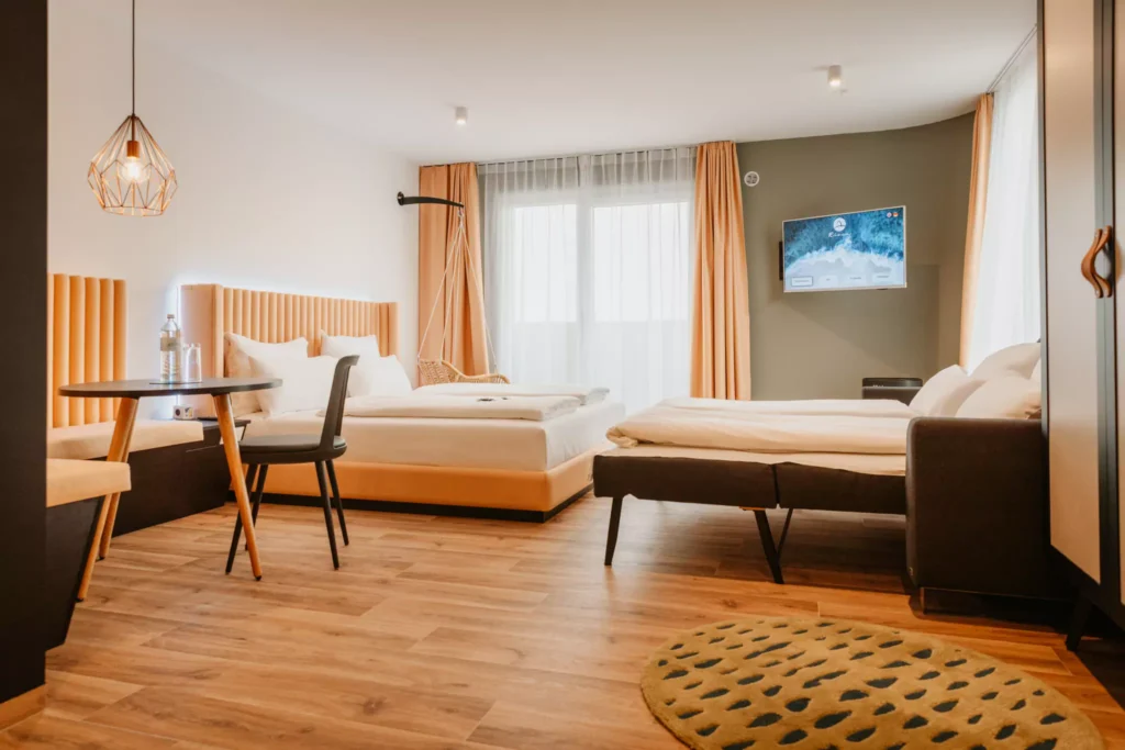 Großes Bett mit weißem Laken vor Schlafsofa