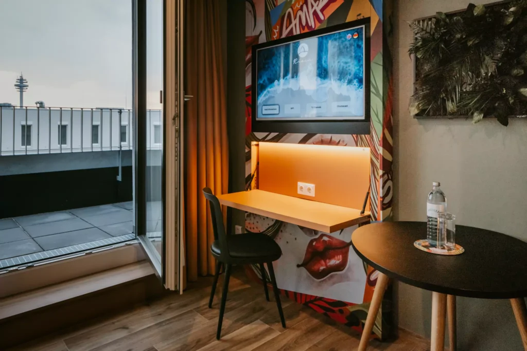 Arbeitsplatz mit bunter wand und schwarzem Stuhl vor TV