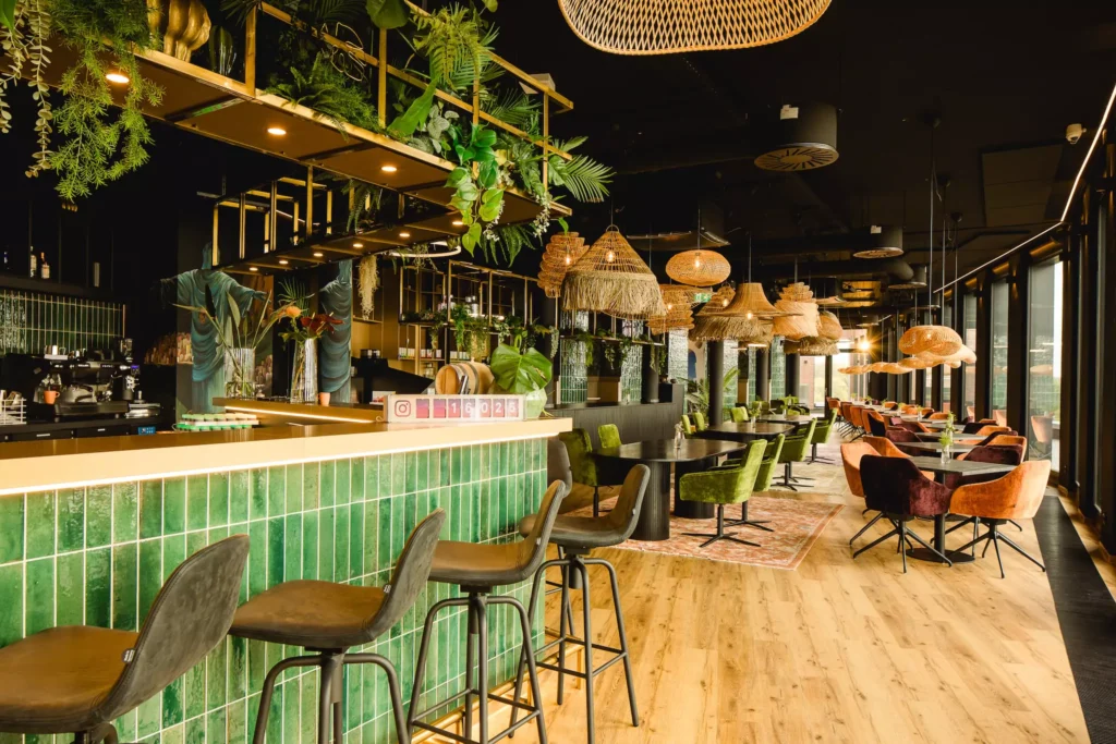 Bar mit grünen Fließen und schwarzen Barhockern