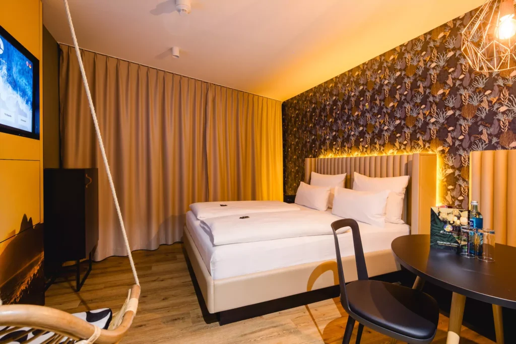 Weißes Doppelbett vor Großem Fenster mit Beleuchtung