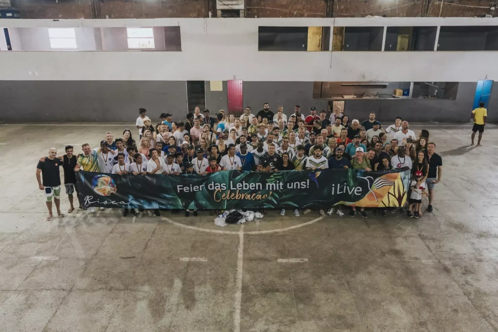 Gruppenbild mit vielen Menschen die ein Plakat von der i Live Group und Rioca hochhalten.