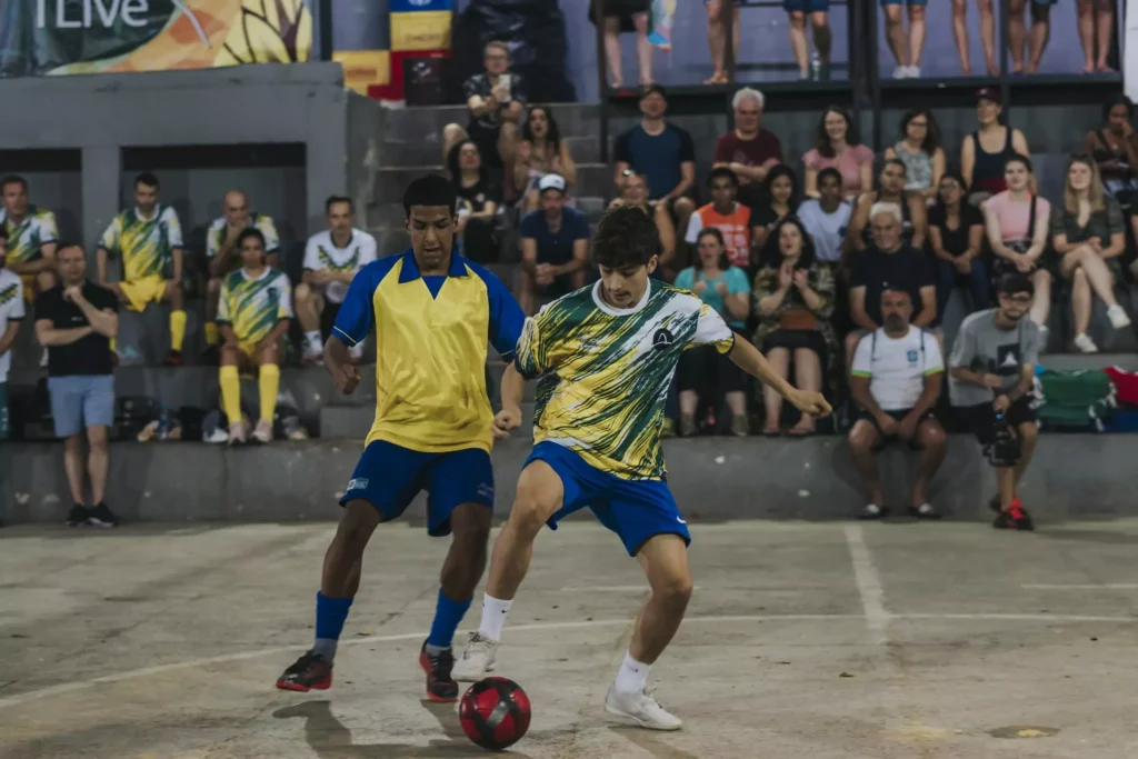 Zwei Jungen im Zweikampf beim Fußballspielen. In Hintergrund sind Zuschauer zu sehen.