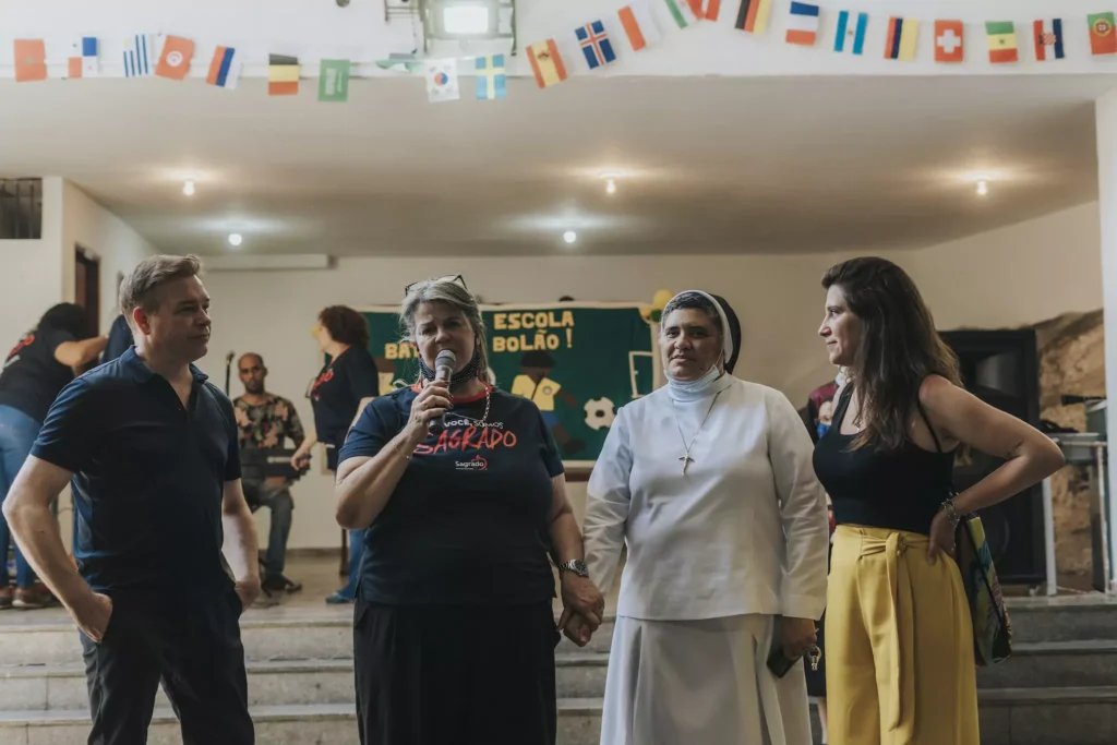 Die Leiterin einer Schule in Rio de Janeiro hält eine Rede. 3 Personen stehen um sie rum und hören zu.
