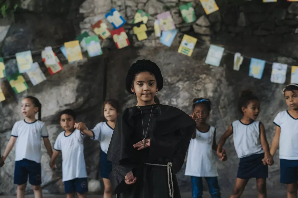 Ein Mädchen einer Schule in einer Favela Von Rio de Janeiro führt einen Tanz auf, im Hintergrund sind weitere Mädchen und halten Händchen