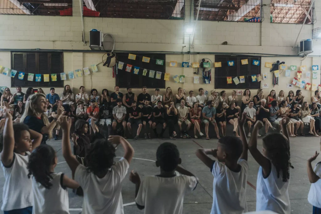 Kinder stehen in einer Schlange und strecken ihre Hände nach oben und führen einen Tanz auf.