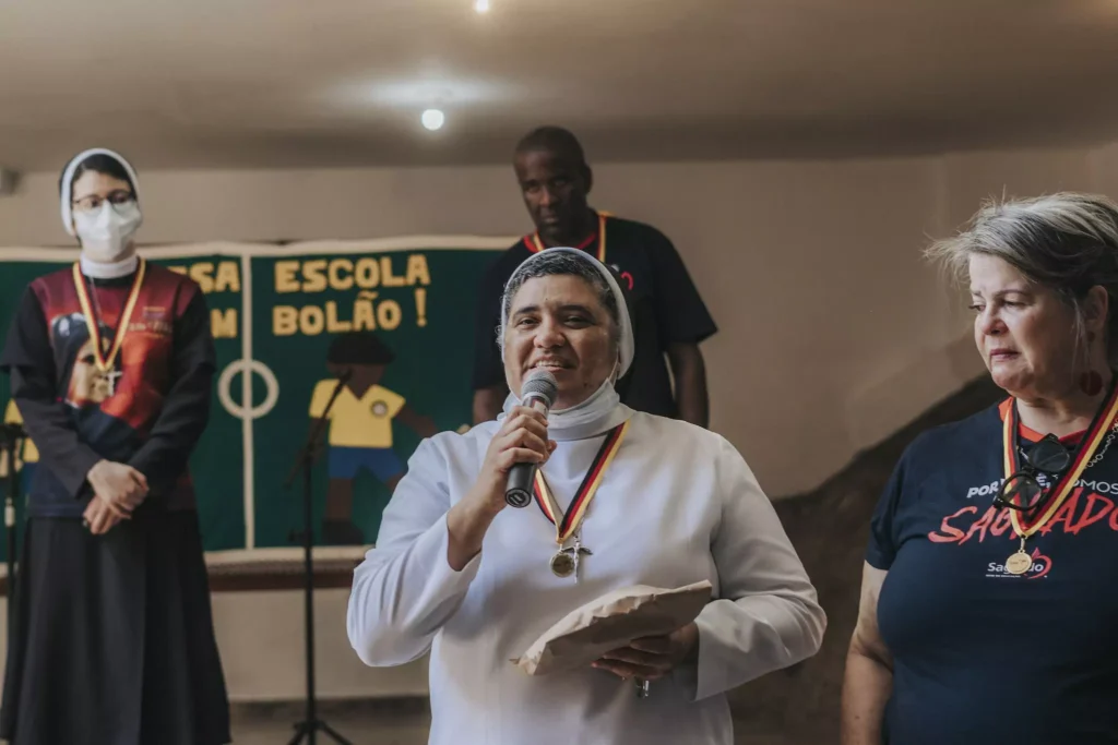 Frau in weißer Robe hält ein Mikrophon in der Hand und hält eine Rede