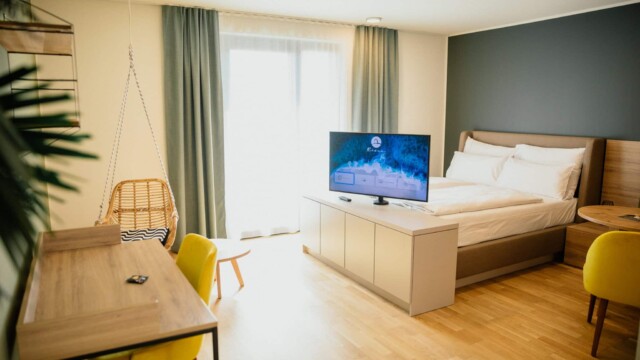 Bett mit weißem Laken und TV im Vordergrund