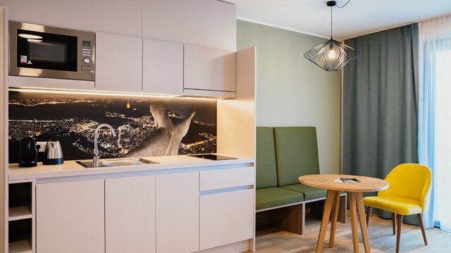 Beige Küchenzeile neben grüner Sitzecke und gelbem Stuhl