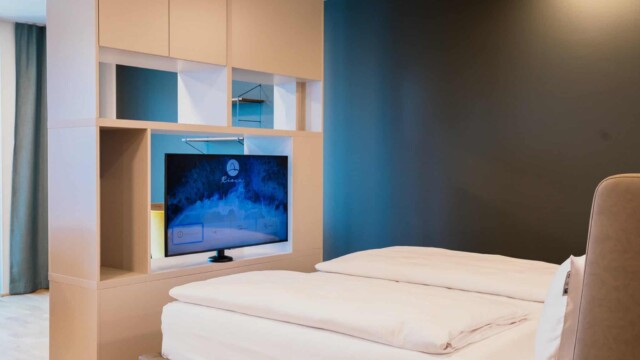 Großes Bett mit weißem Laken und TV