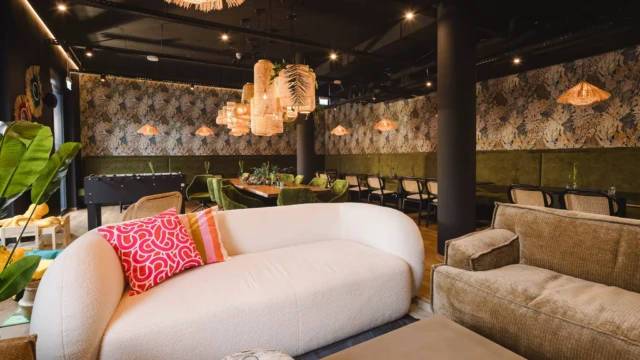 Hotellobby mit vielen Sitzgelegenheiten im Hintergrund und einer großen beigen Couch im Vordergrund.