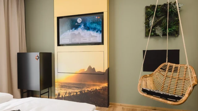 Hängestuhl und TV in Hotelzimmer mit grüner Wand.