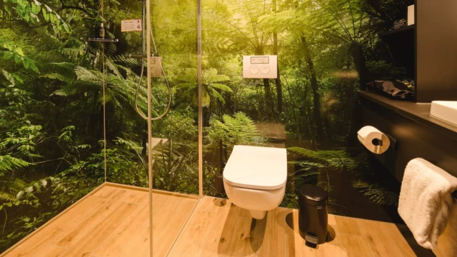 Hotelbad mit Regendusche und Toilette. Daneben befindet sich ein schwarzer Schrank mit einem weißen modernen Waschbecken.