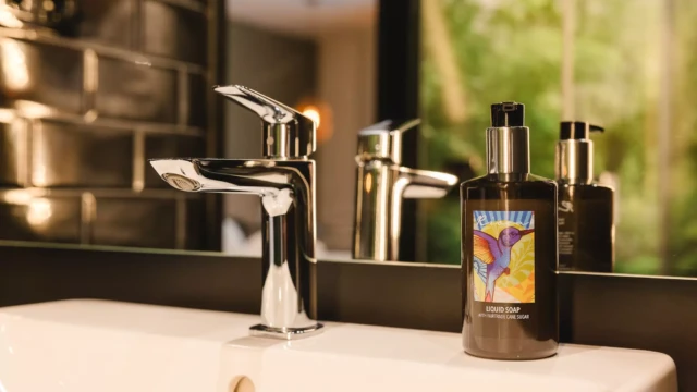 Waschbecken mit moderner Armatur und Seifenspender in einem Hotelbad.