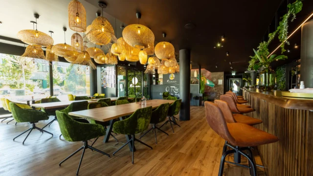 Frühstücksbereich von Design Hotel mit bunten Stühlen und schwarzen Tischen.