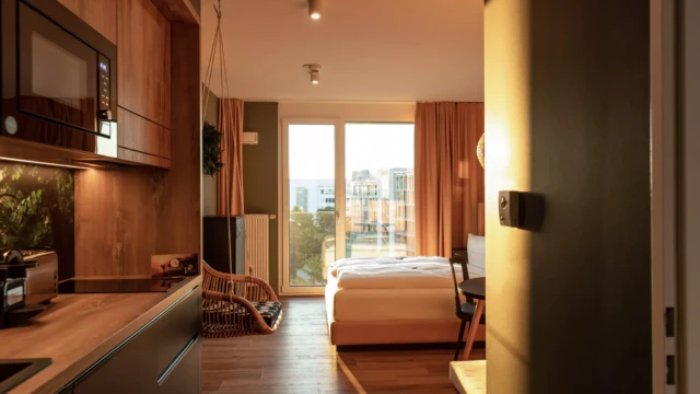 Design Hotel in München mit großem Doppelbett, Küche und Badezimmer.