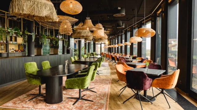 Grüne Stühle an schwarzem Tisch mit beigen Deckenlampen aus Rattan