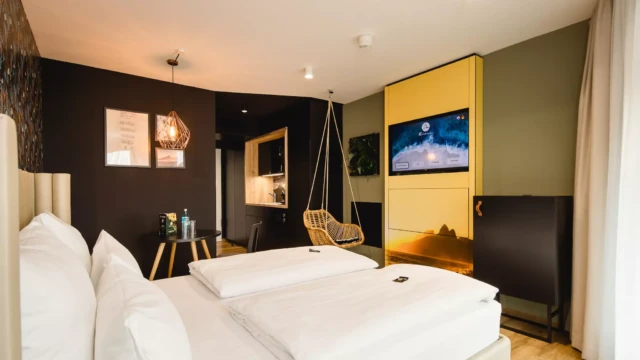 Doppelbett vor TV und Küchenzeile