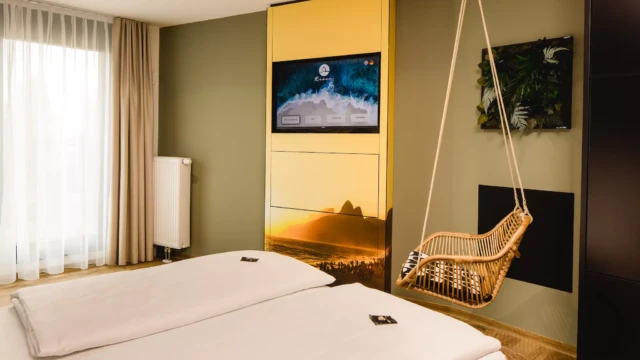 Doppelbett mit weißem Laken vor grüner Wand